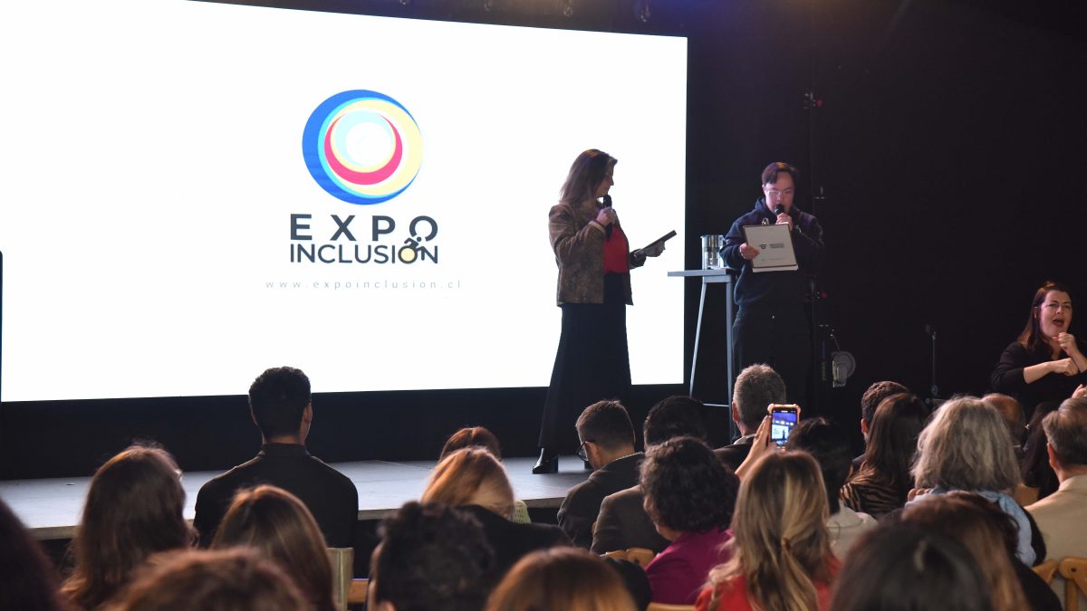 Mujer en un escenario con pantalla LED a sus espaldas con el logo Expo Inclusión