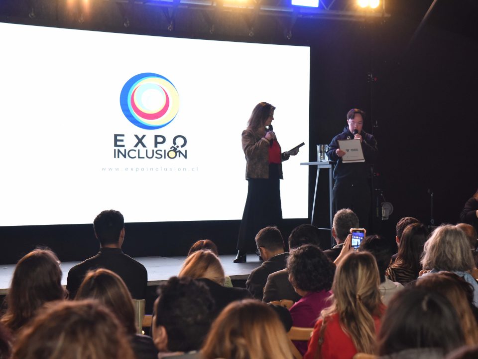 Mujer en un escenario con pantalla LED a sus espaldas con el logo Expo Inclusión